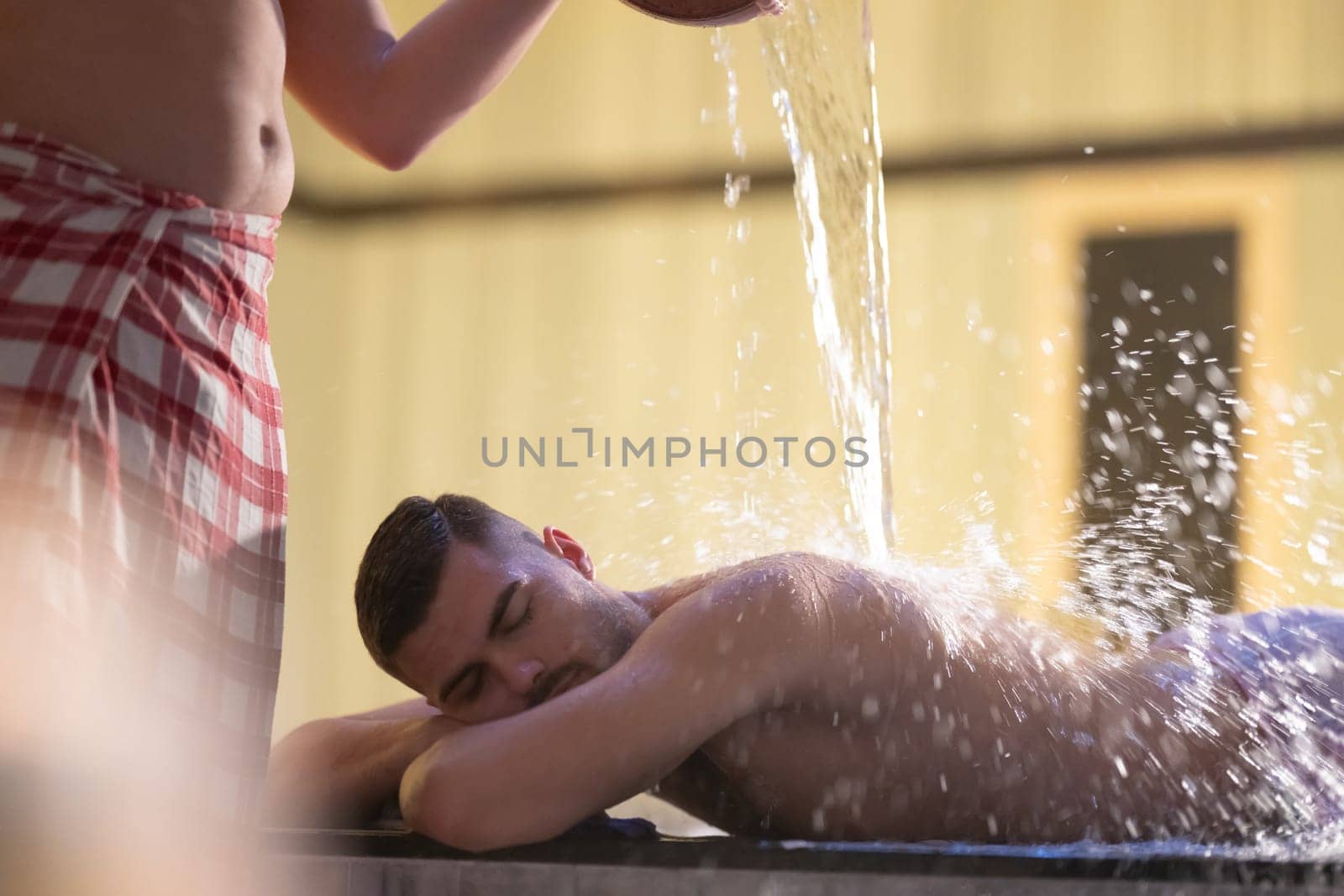 Water Treatment in Turkish Hammam.Man receiving water therapy inside a traditional Turkish hammam with ornate details.
