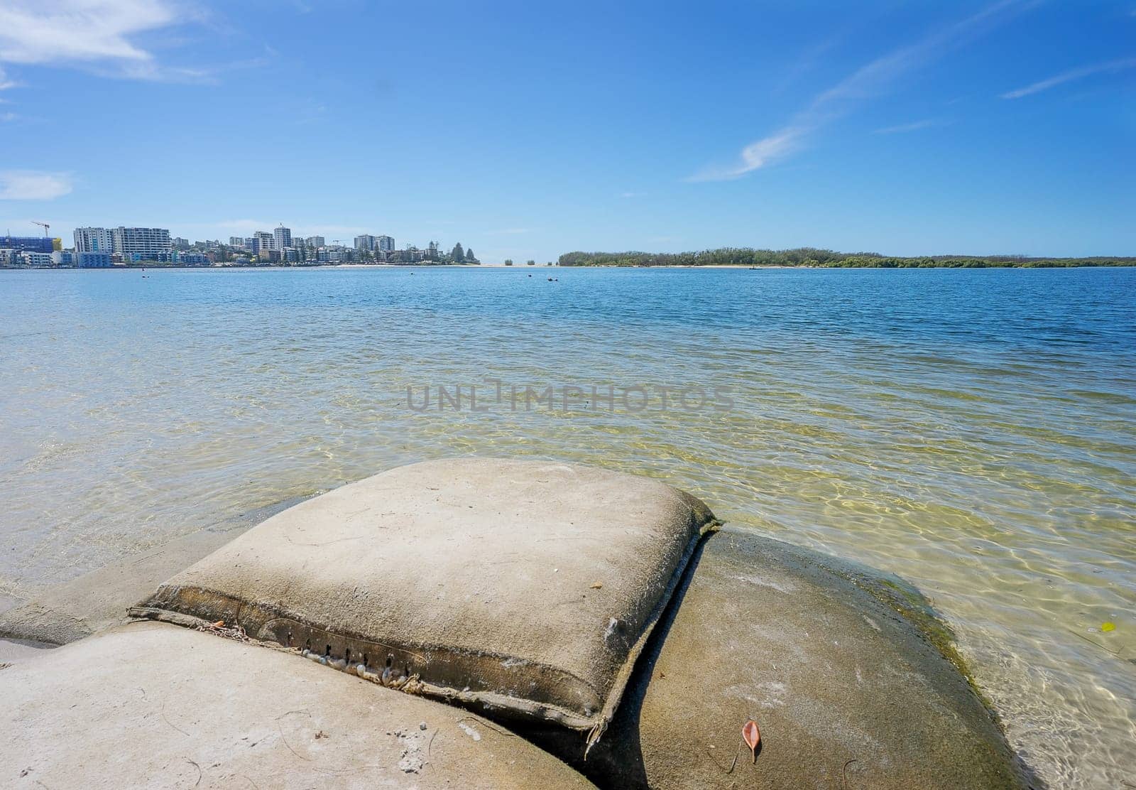 Looking across from sandbags used for erosion on Golden Beach towards Caloundra City buildings and  Bulcock Beach and across to the vegetation on the northern tip of Bribie Island