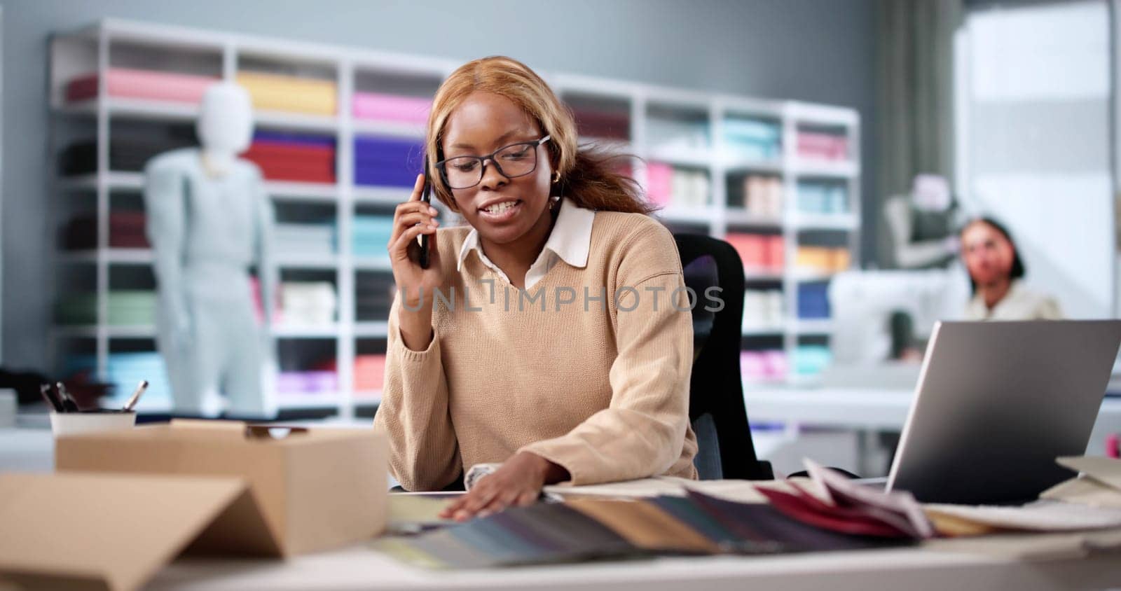 Fashion Designer Creating New Designs On Smartphone In Small Studio.
