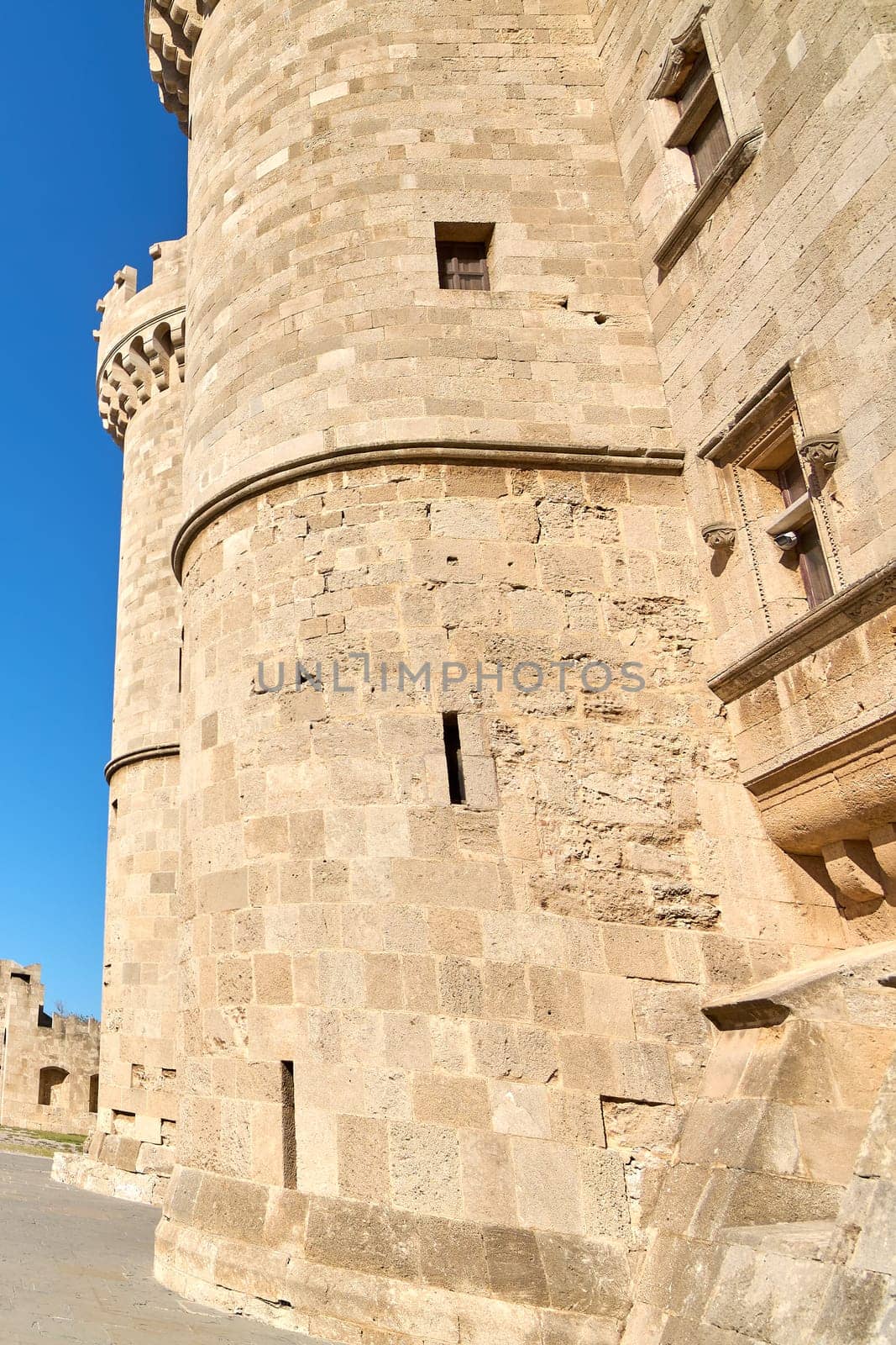 Close-up of an ancient castle's textured stone walls and circular tower, highlighting the historical architecture under bright daylight.