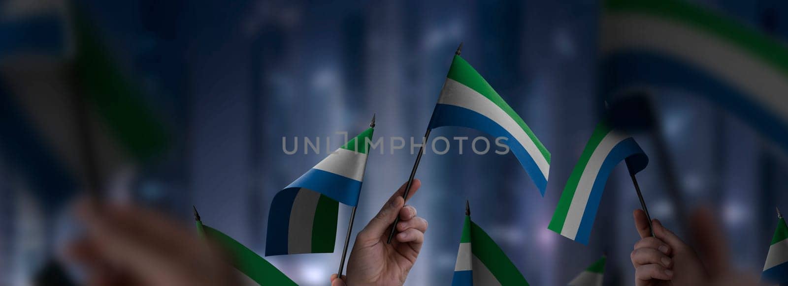 Sierra Leone flags in their hands on a blurred urban background. The photo illustration was created without the use of artificial intelligence, only using Photoshop.