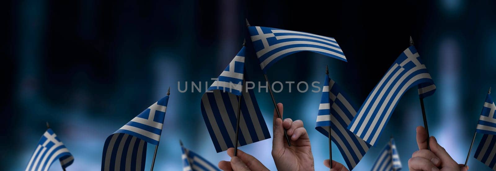 Greece flags in their hands on a blurred urban background. The photo illustration was created without the use of artificial intelligence, only using Photoshop.