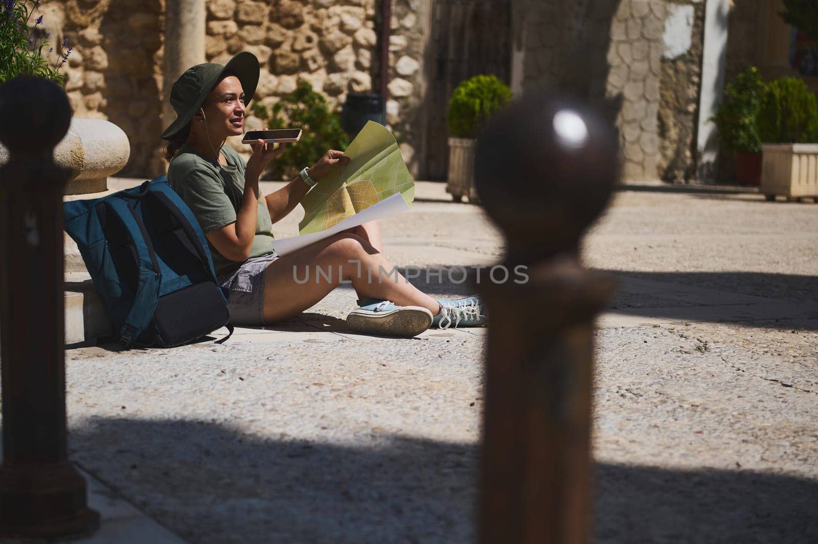 A tourist sits in a historical town square, holding a map and using mobile navigation. Surrounded by traditional architecture, they exude curiosity and adventure.