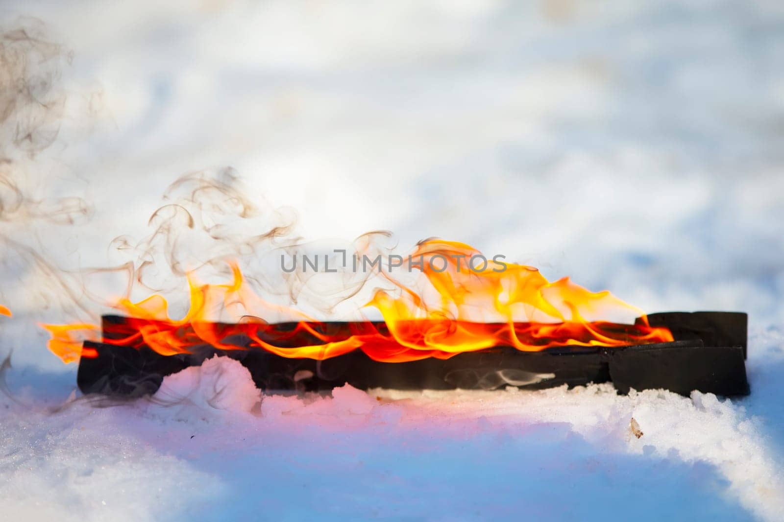 Burning log in the snow. Fire on a wooden stick.