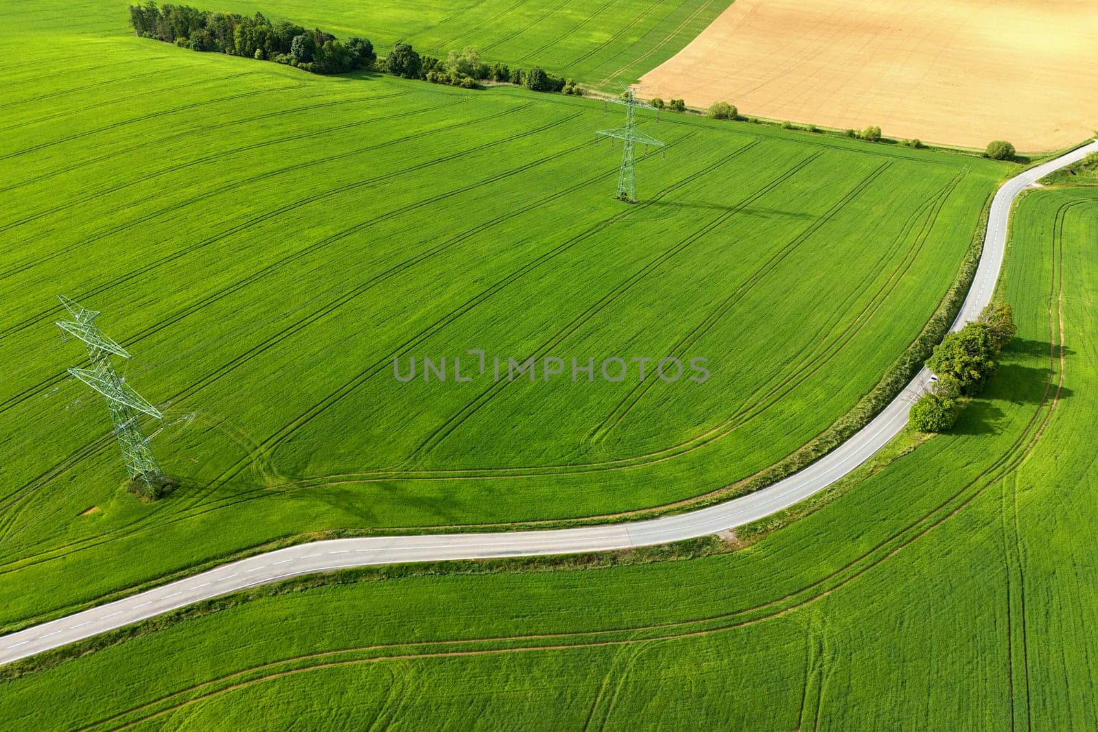 Road with cars between green fields from above - view of nature from a drone. Beautiful landscape concept suitable for transportation, agriculture and environment.