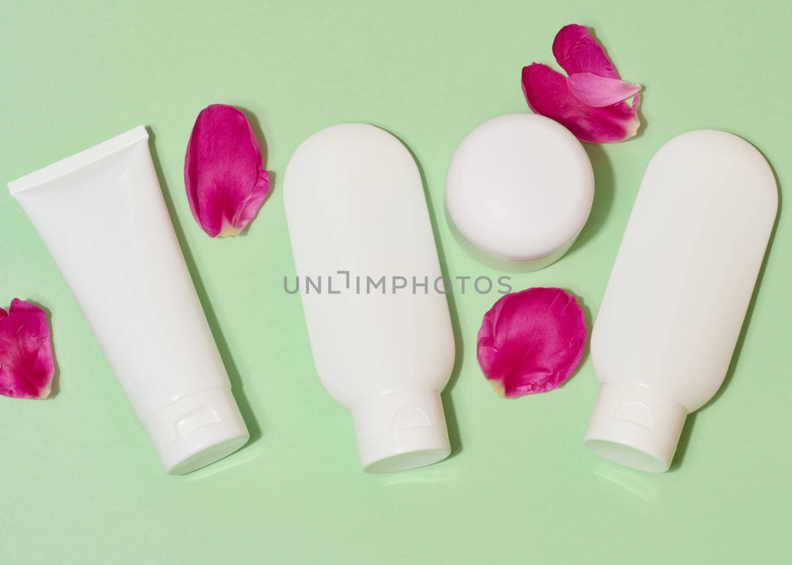 Top view of cosmetic tubes without labels in white packaging, light green background