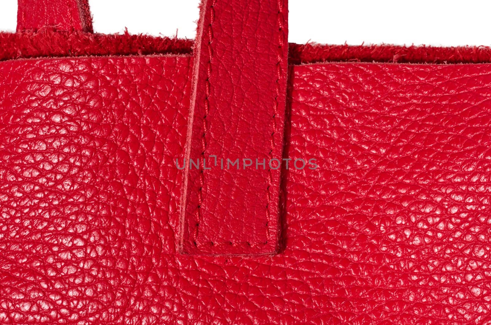 A fragment of the handle of a red leather bag, showing the grainy texture of the material and the quality of the stitching