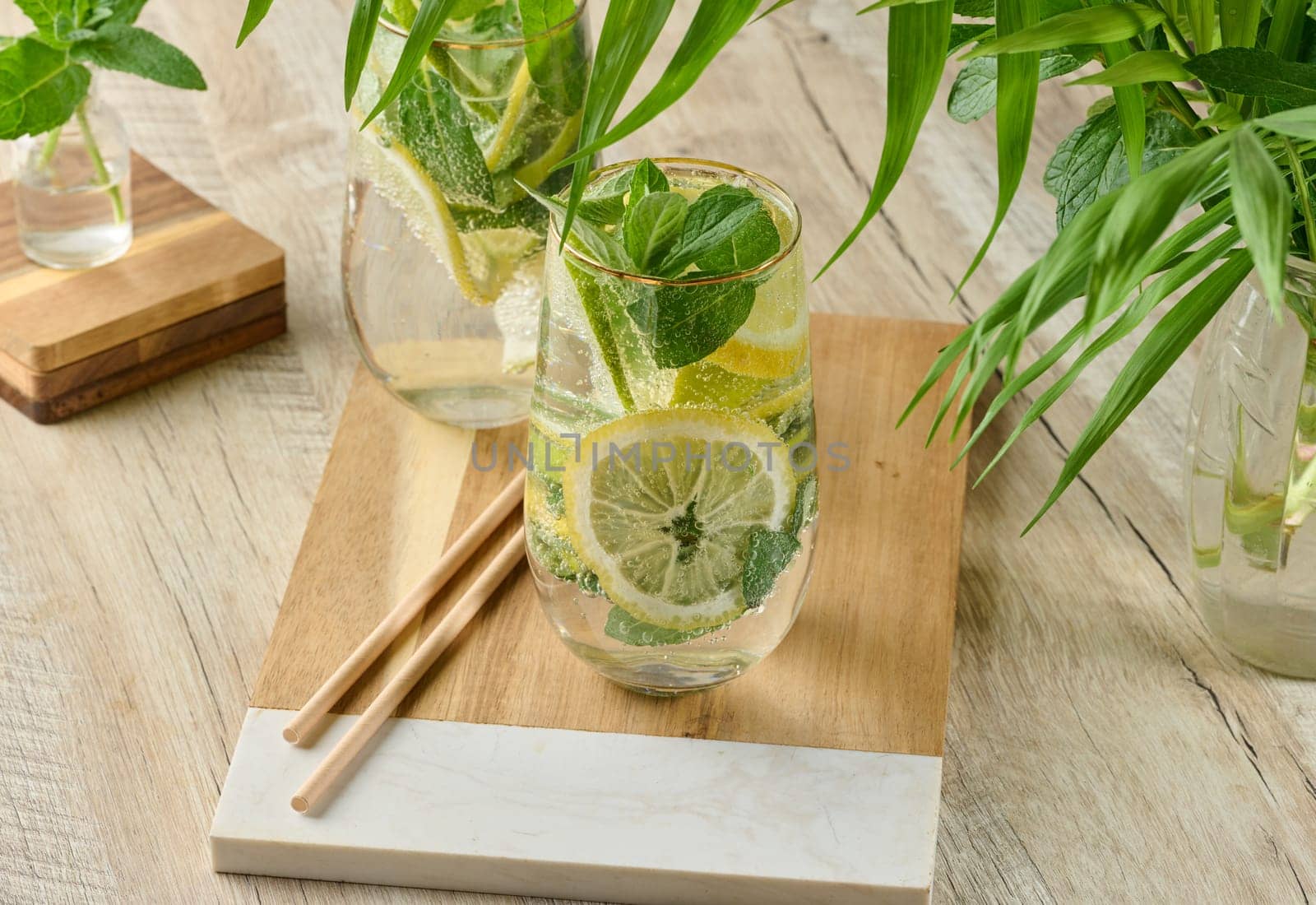 Refreshing citrus and mint drink in glasses with ice, lemon, lime, and mint leaves. Healthy summer beverage