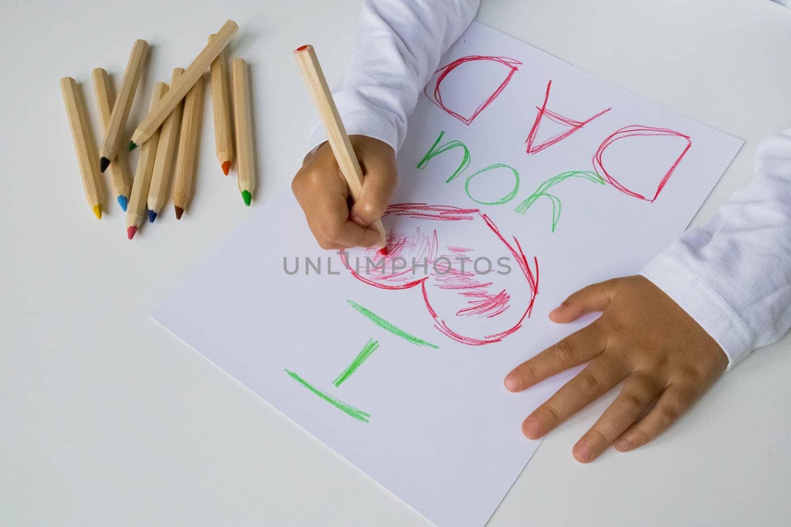 Child drawing I love you dad with colored pencils. Father day.