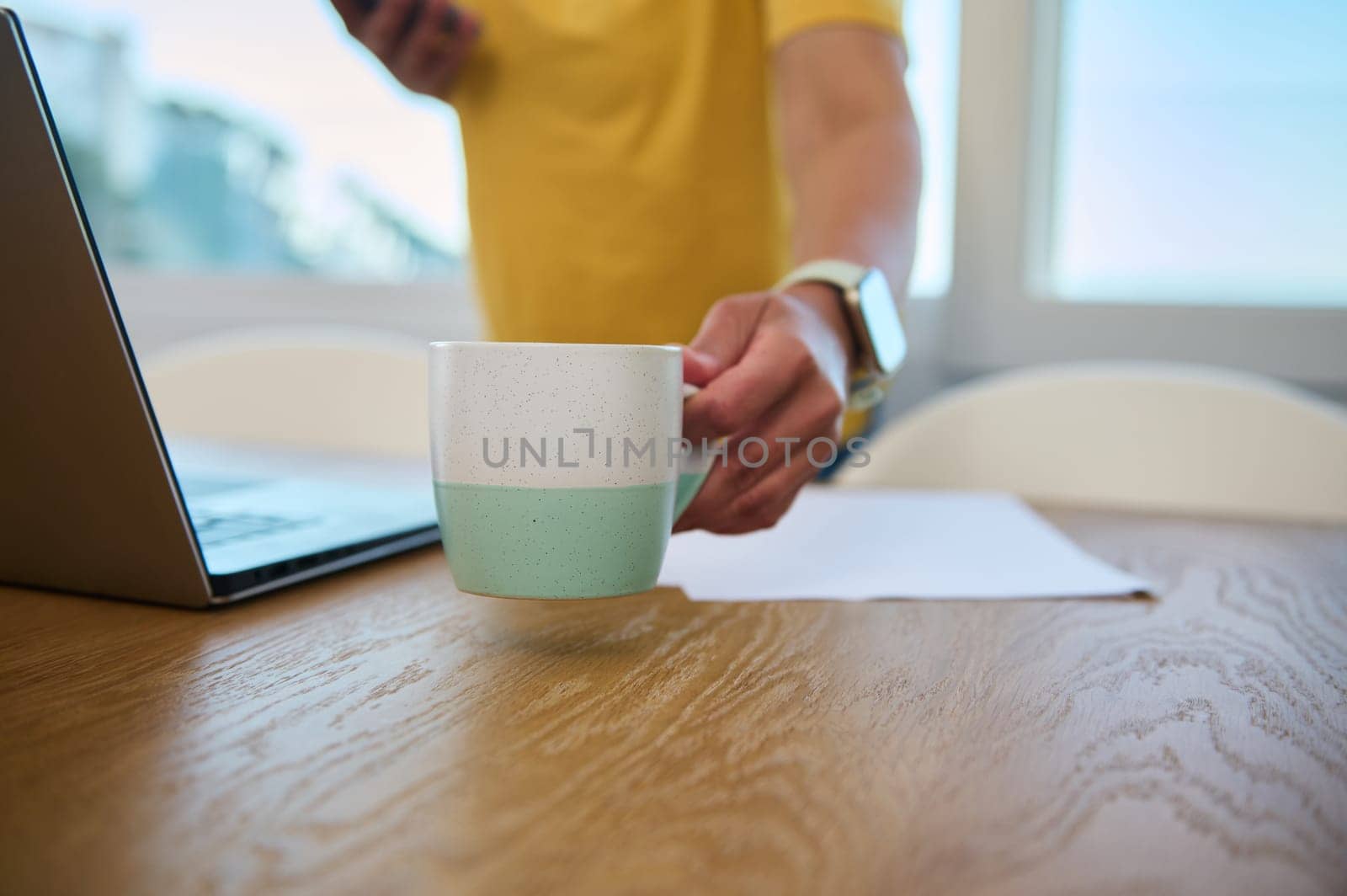 A casual scene showcasing a person enjoying a coffee moment while working at home, symbolizing productivity and relaxation in a cozy atmosphere.