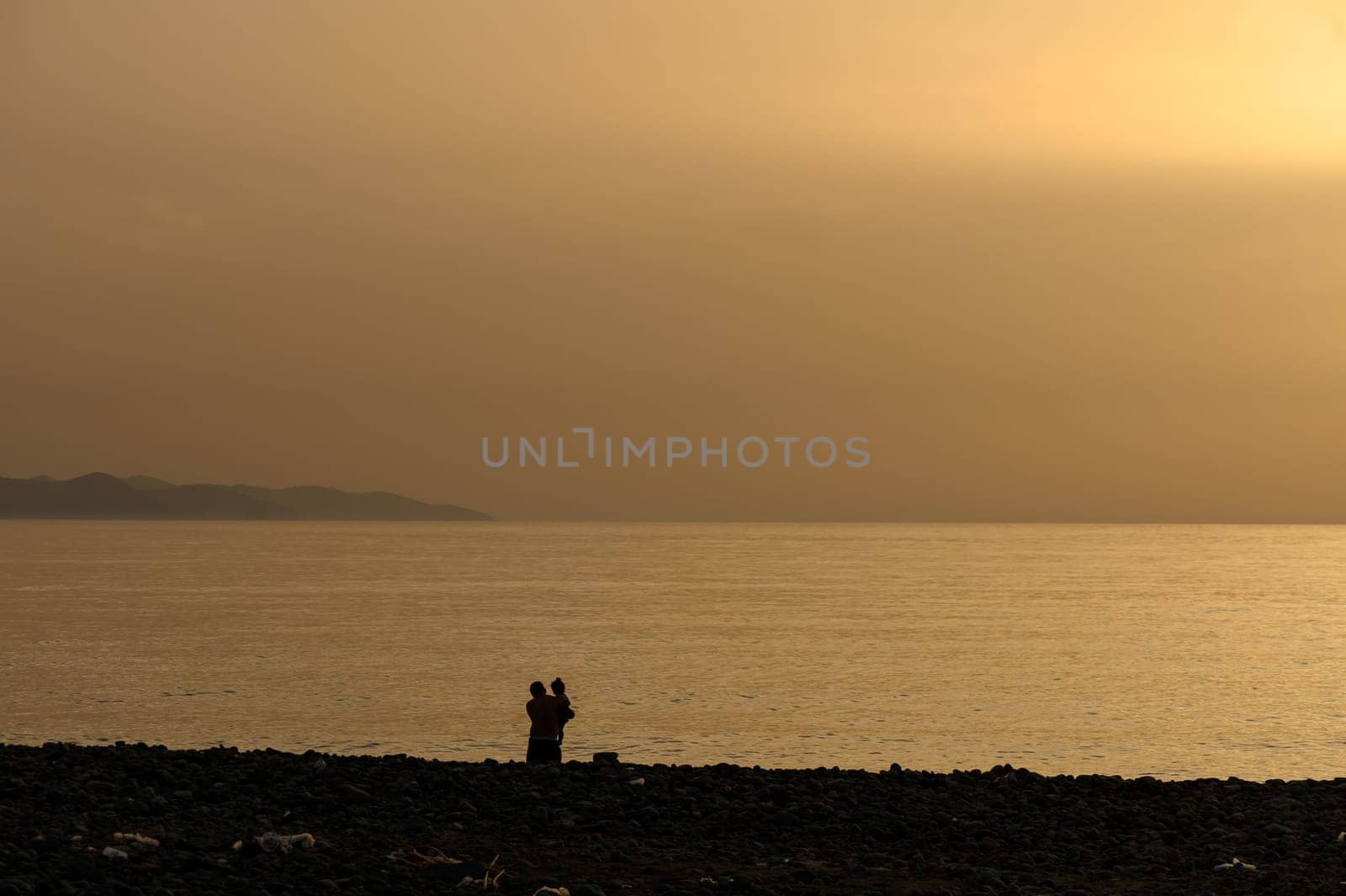 Father holds his young child on the beach in Cyprus