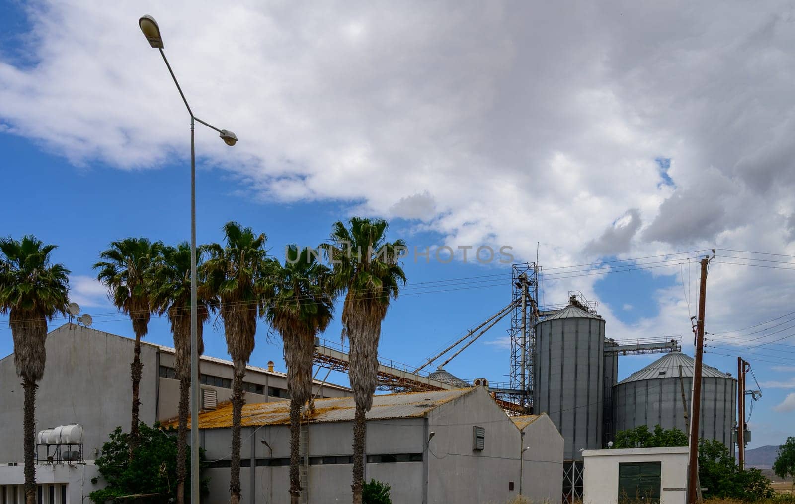 Large grain elevator facility located in the Cypriot countryside, used for storing and processing harvested cereals like wheat and barley.