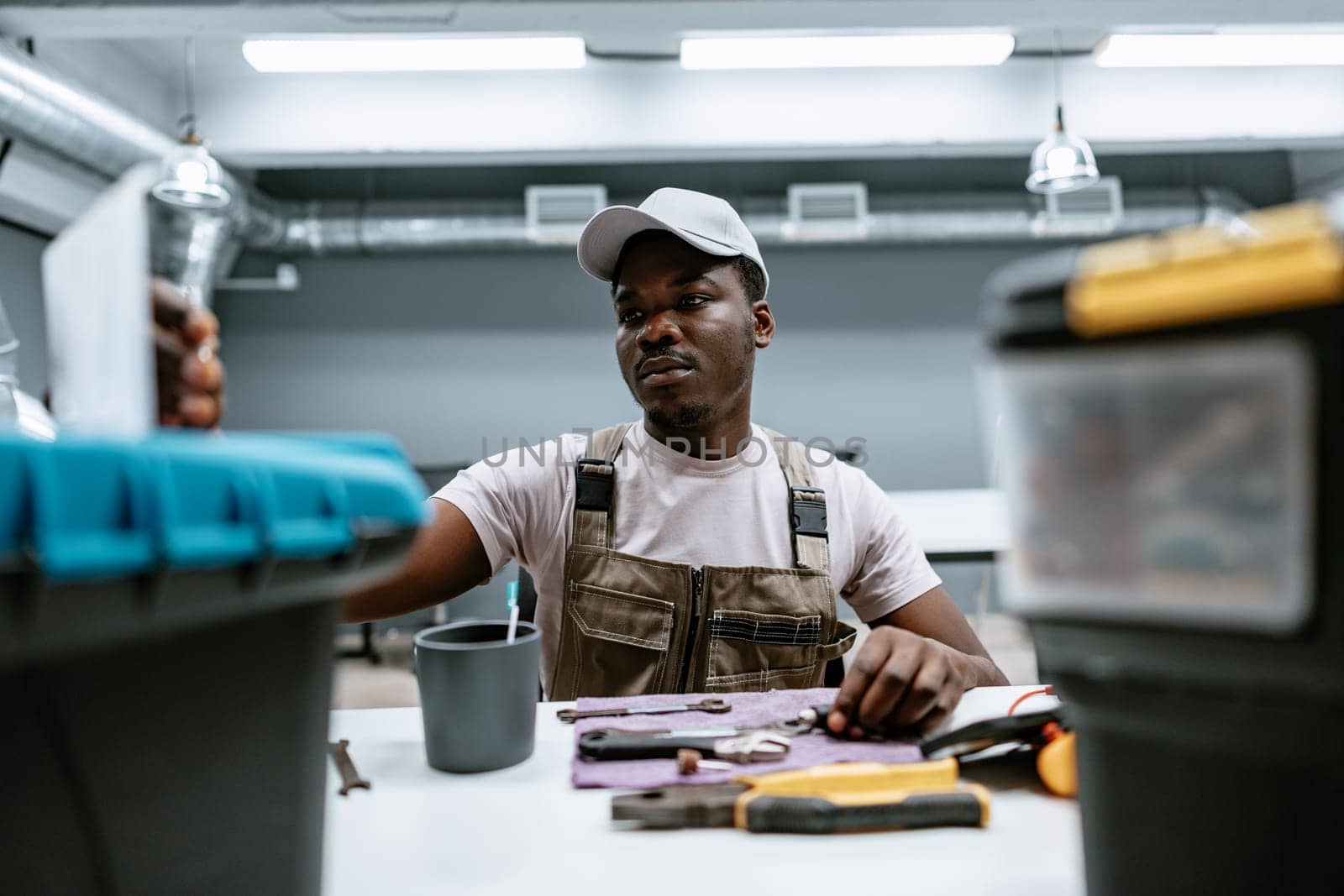 A focused worker is arranging various tools and materials in a bright, well-equipped workshop during the day. The workspace is clean and organized, showcasing professionalism.