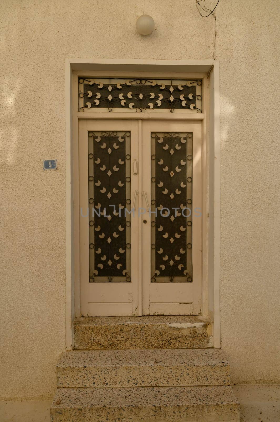 Weathered white wooden door with rustic texture on a traditional home in Cyprus, evoking Mediterranean charm.