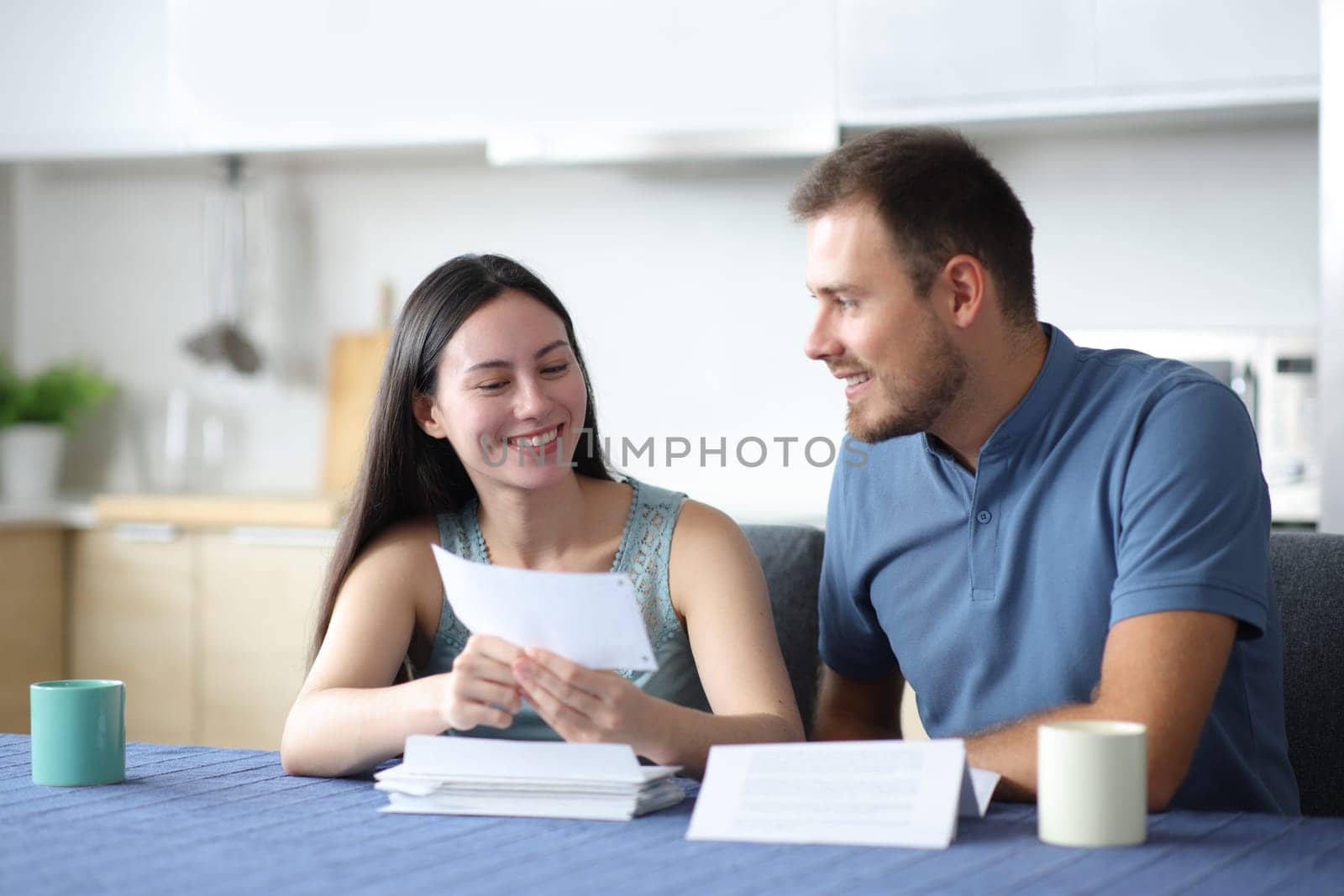 Happy interracial couple talking about letter in the kitchen at home