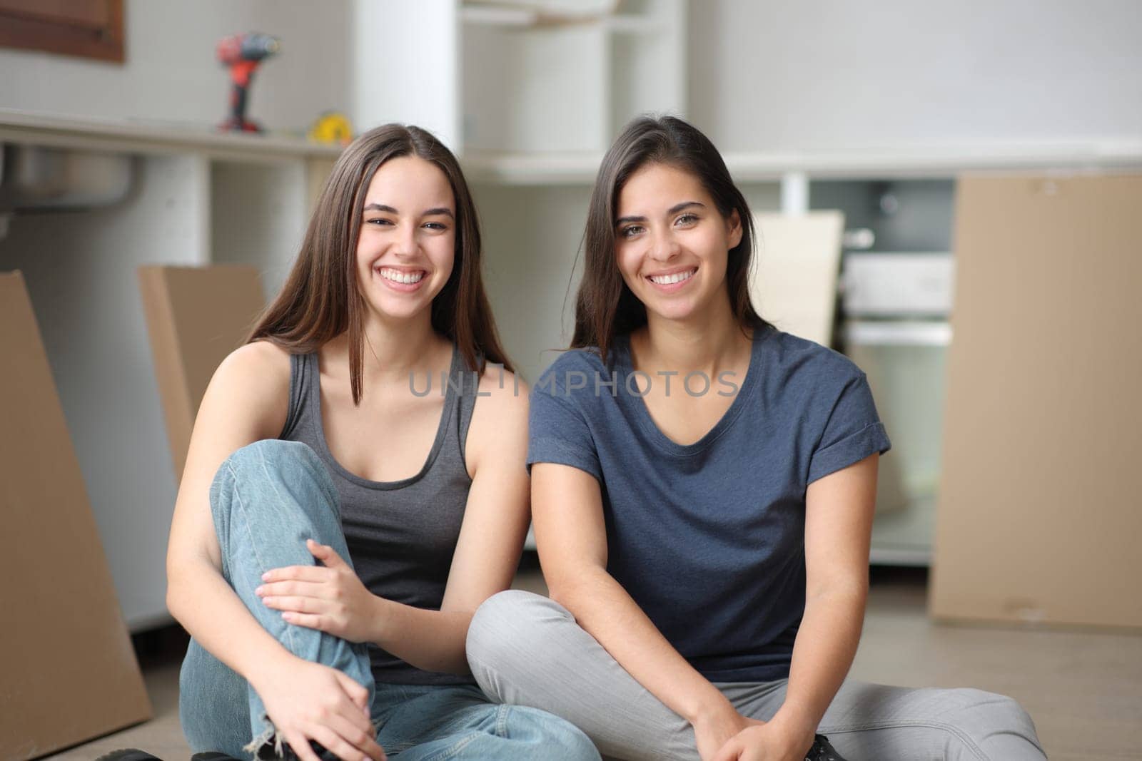 Front view portrait of two happy roommates posing in a house under reformation