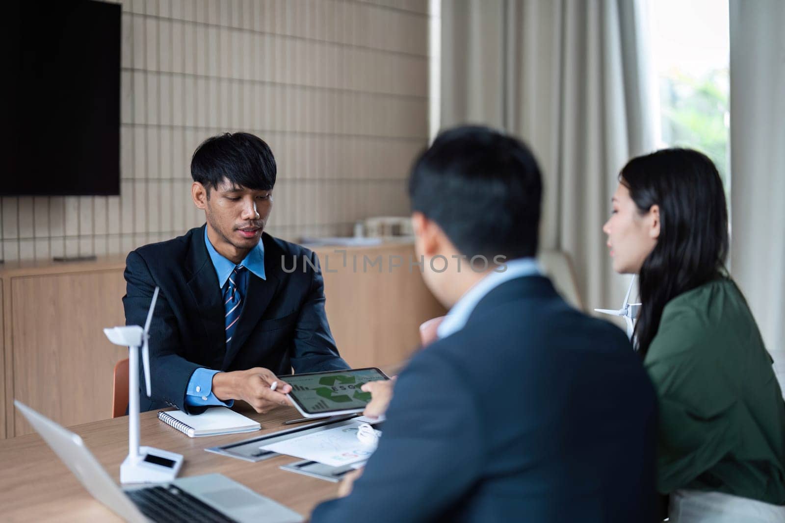 Business professionals engage in a discussion about ESG strategies, focusing on sustainability and corporate governance in a modern office.