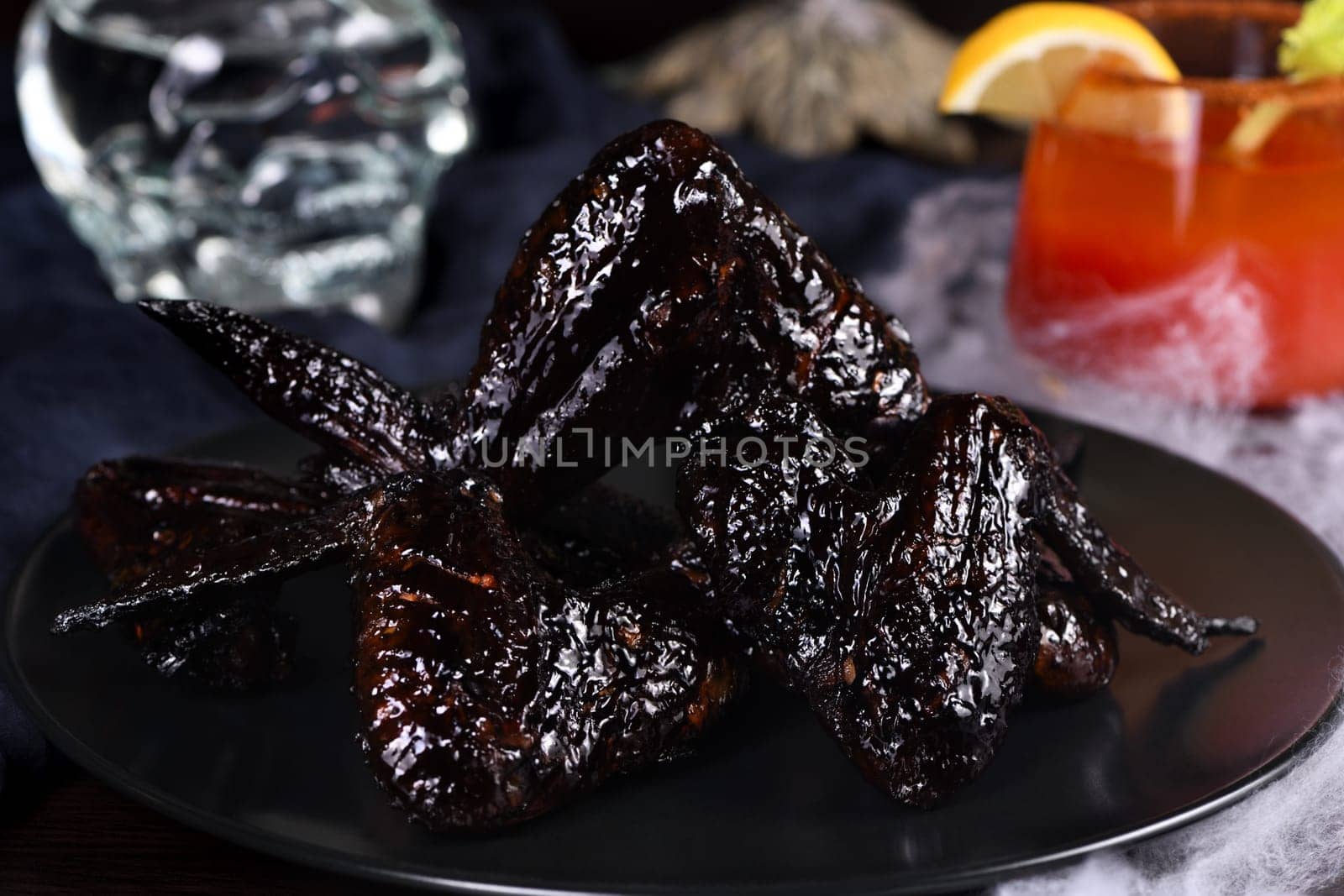 Bat wings. Cooked in sweet and sour sauce with cuttlefish ink, served with ketchup on a plate. An original idea for a Halloween party