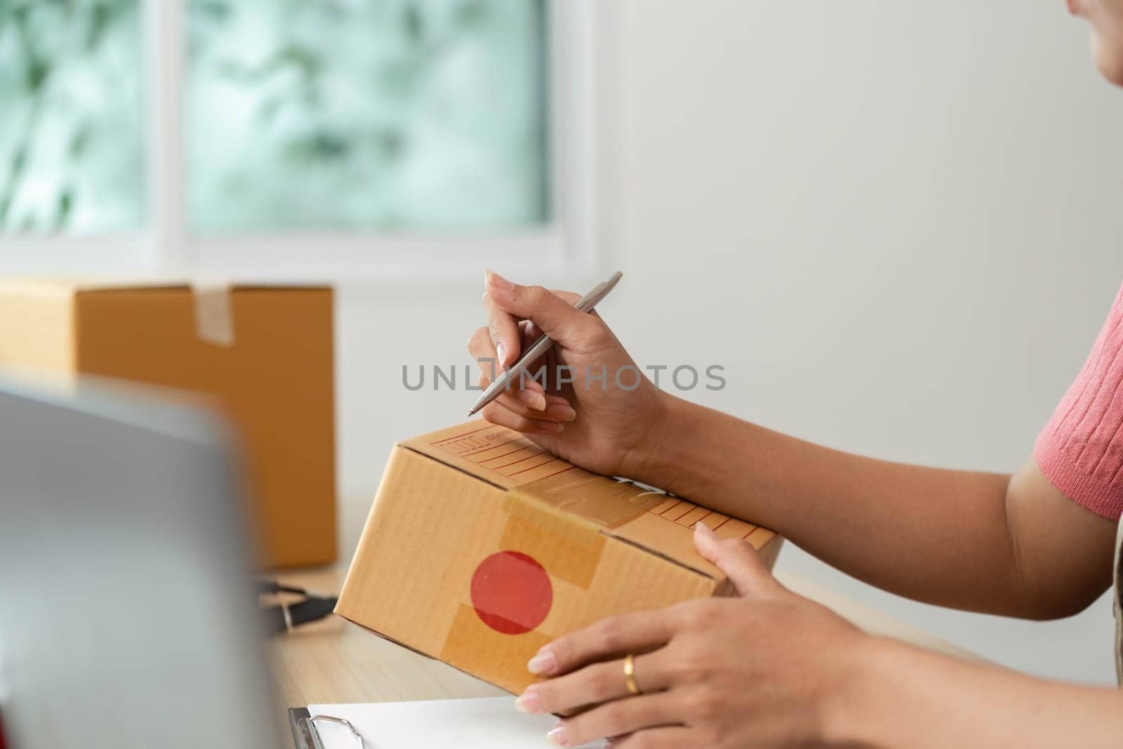 A woman focuses on packaging a product, ensuring everything is ready for dispatch, representing her small business dedication.