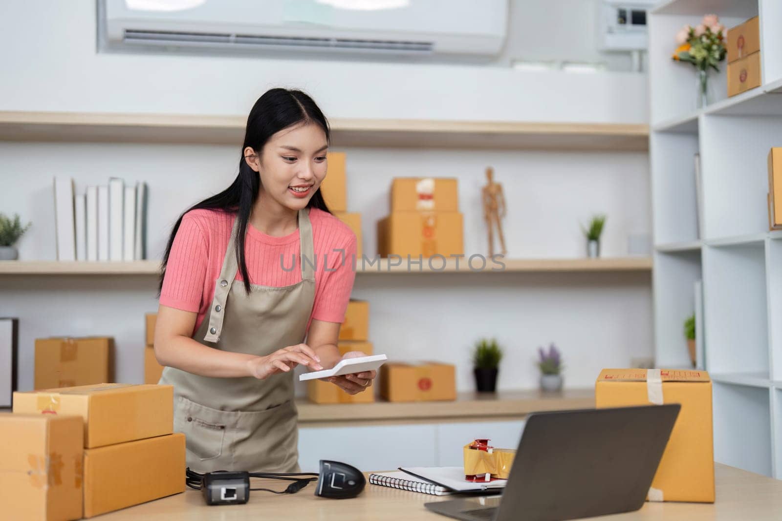 A focused entrepreneur jotting down important details while managing her packages, showcasing the essence of small business operations.