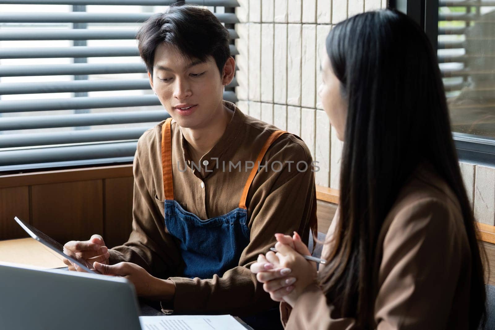 Two young professionals engage in a collaborative discussion, sharing ideas and insights in a contemporary office environment.