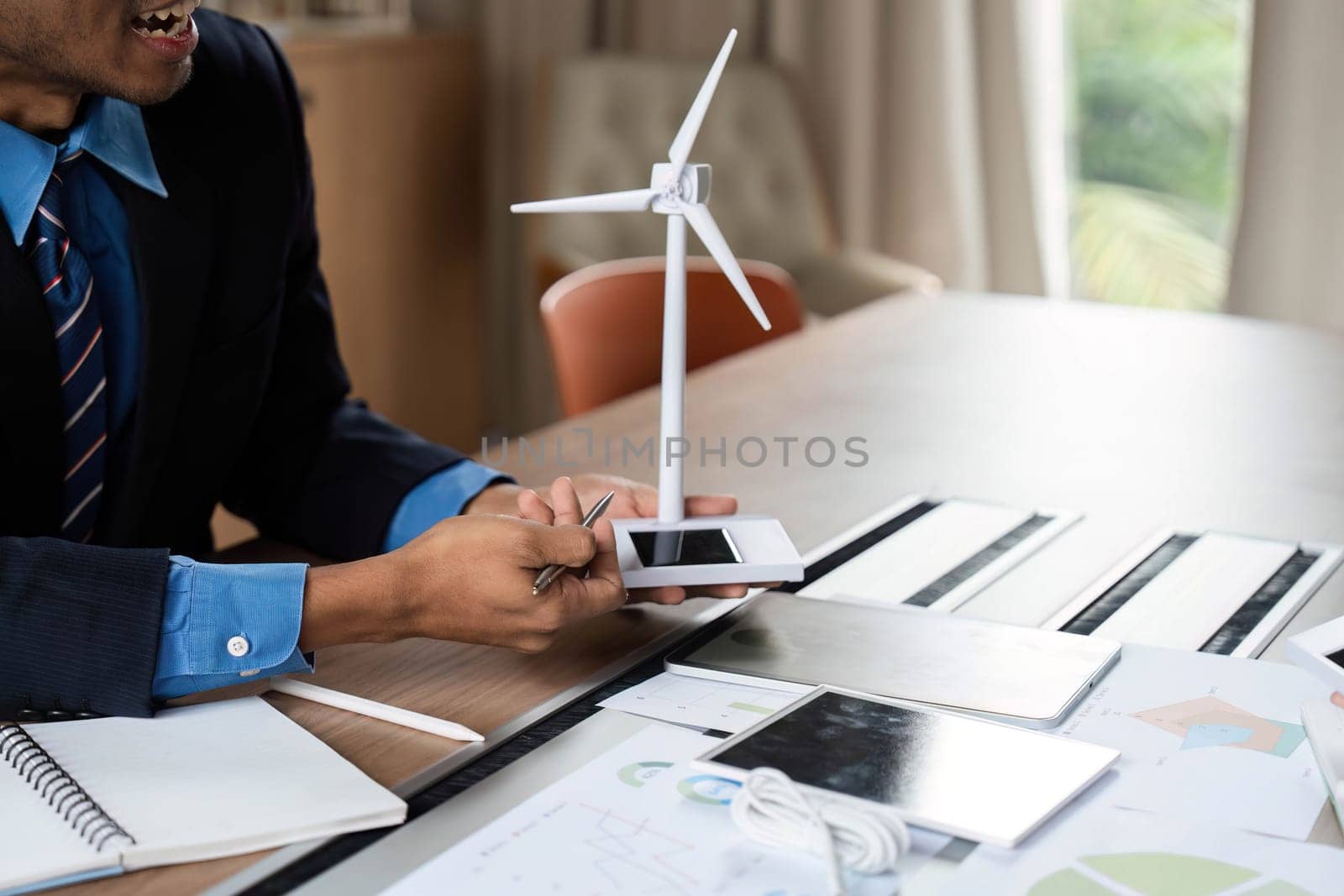 A businessman presents a wind turbine model, emphasizing sustainable energy solutions in an ESG meeting.