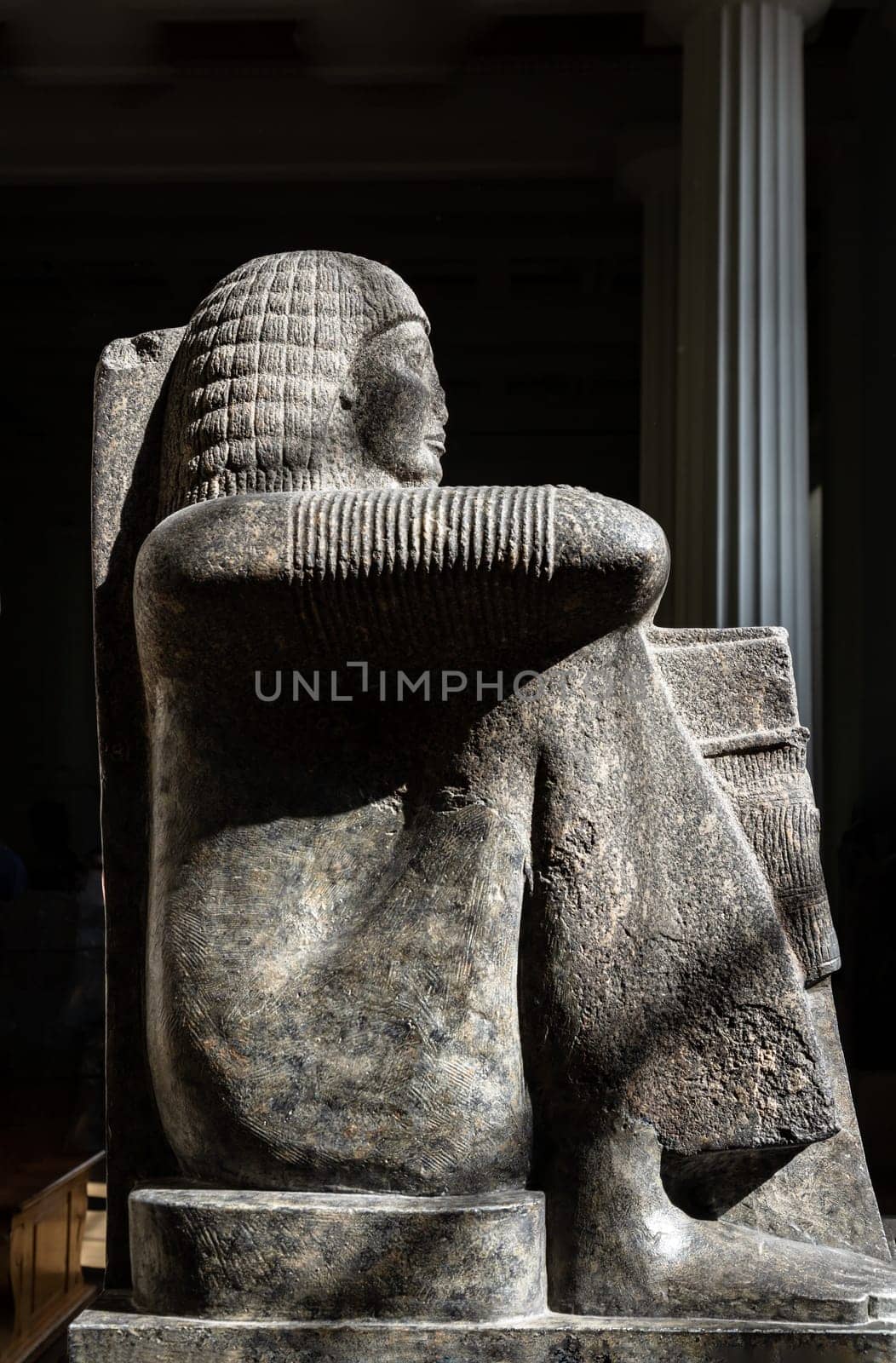 London, UK - May 31, 2025 - Granodiorite figure of Roy, well-known high-priest of Amun-Ra in Thebes, squatting with his arms crossed on his knees, at the British Museum. use it as your Wallpaper, Poster and Space for text, Selective focus.