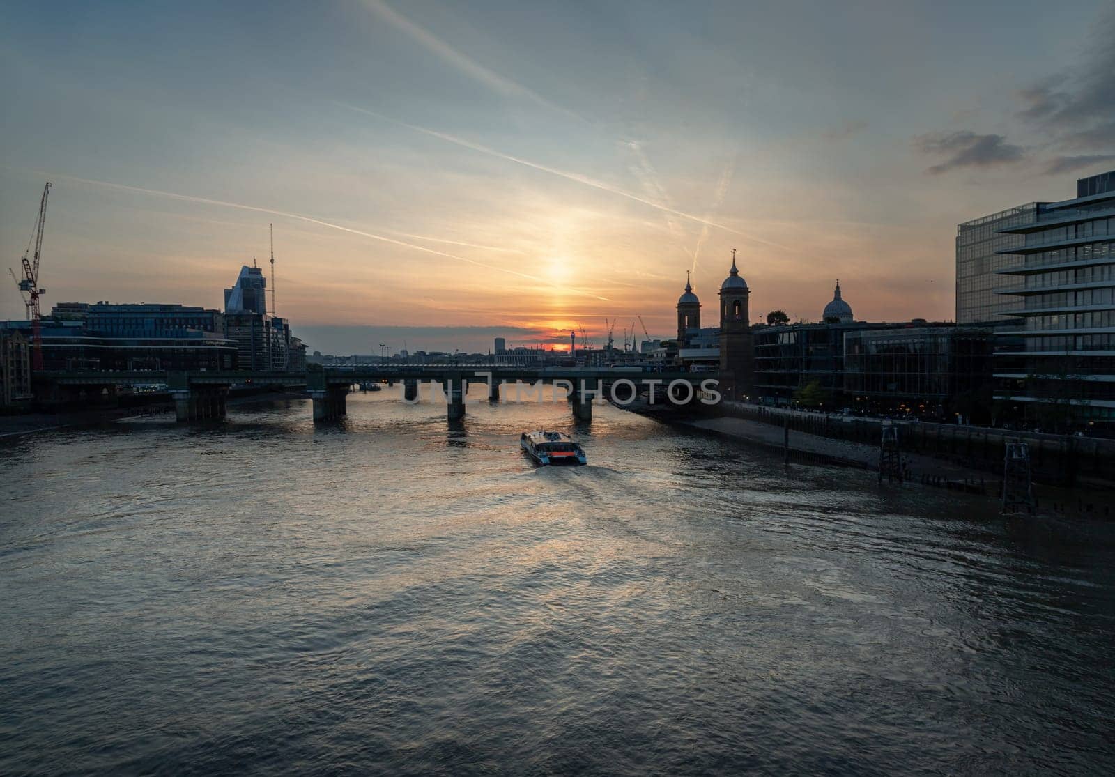 London, UK - Apr 27, 2025 - A stunning silhouette view of Cannon street railway station bridge with Cruise boat on River thames and colour sky in the background. use it as your Wallpaper, Poster and Copy space, Selective focus.