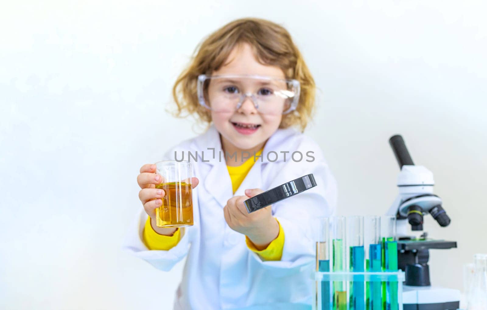 Laboratory examination of a child with test tubes, reagents and a microscope. Selective focus. kid.