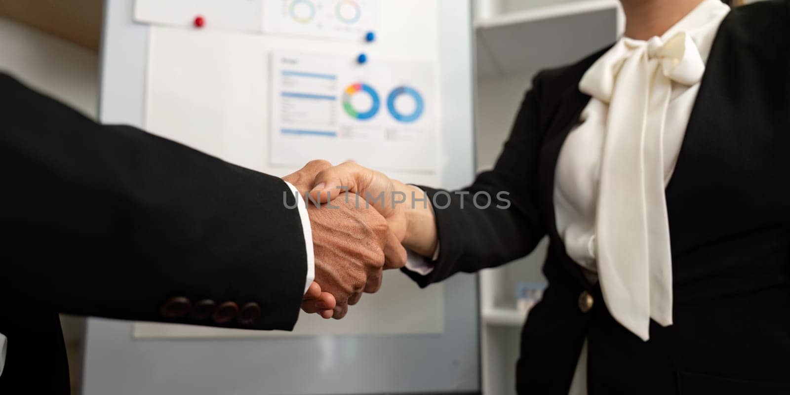 Two business professionals shaking hands, symbolizing a successful agreement following a presentation. Focus on collaboration and trust.