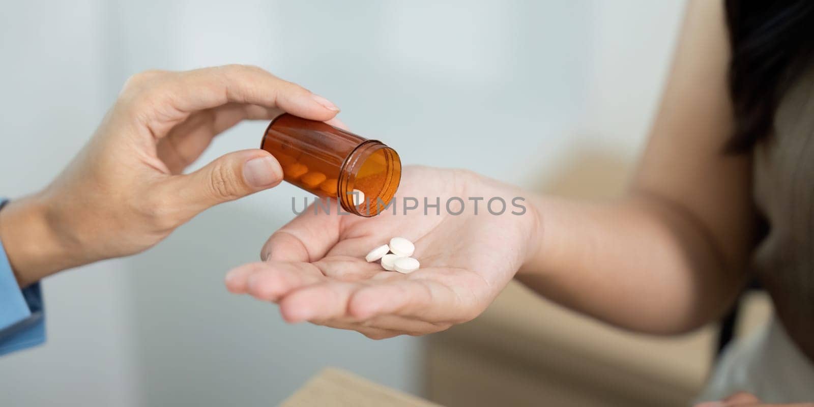 A healthcare worker dispenses pills from a prescription bottle to a patient hand, illustrating personal care and attention.
