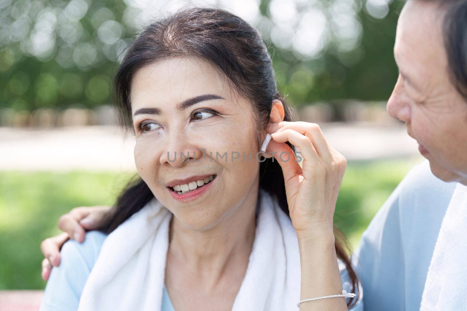 A senior couple shares a moment of connection as they listen to music together while exercising, showcasing the blend of wellness and technology in their active lifestyle.