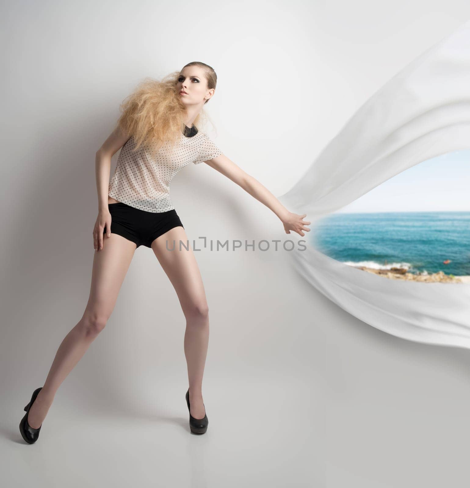 full-length portrait of pretty blonde girl with fashion style and creative hair-style. She wearing pois shirt, sexy shorts and black heels