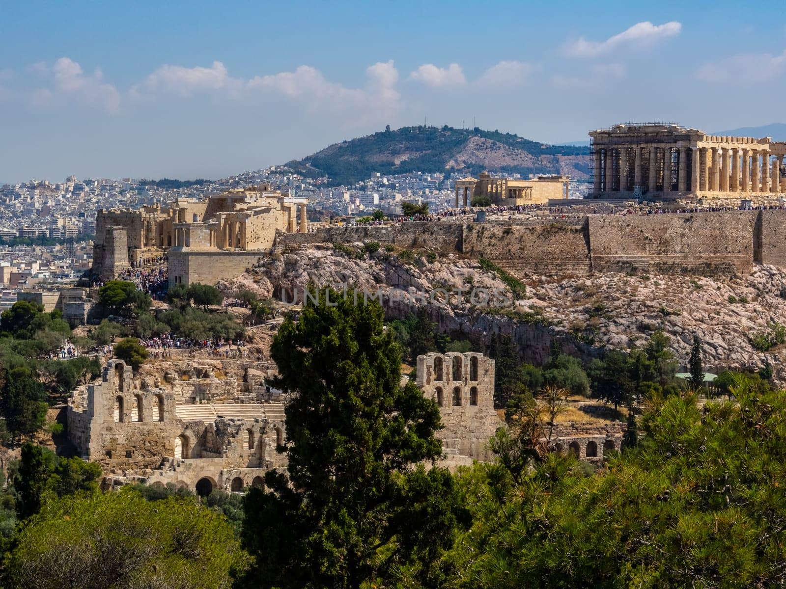 Panoramic view of Athens and Acropolis hill shot from Hill of Muses at clear summer day. Iconic view of ancient ruins and modern city with its main sights.