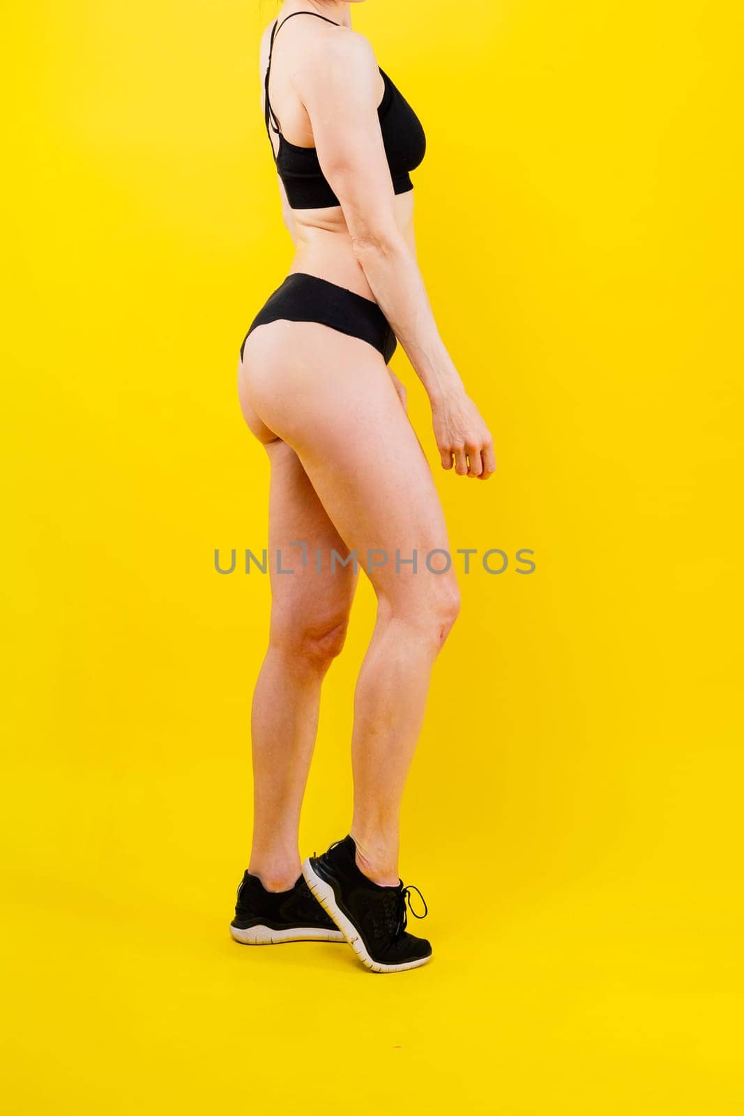 Fit sportswoman in leggings and sports bra looking away and while standing on a yellow red