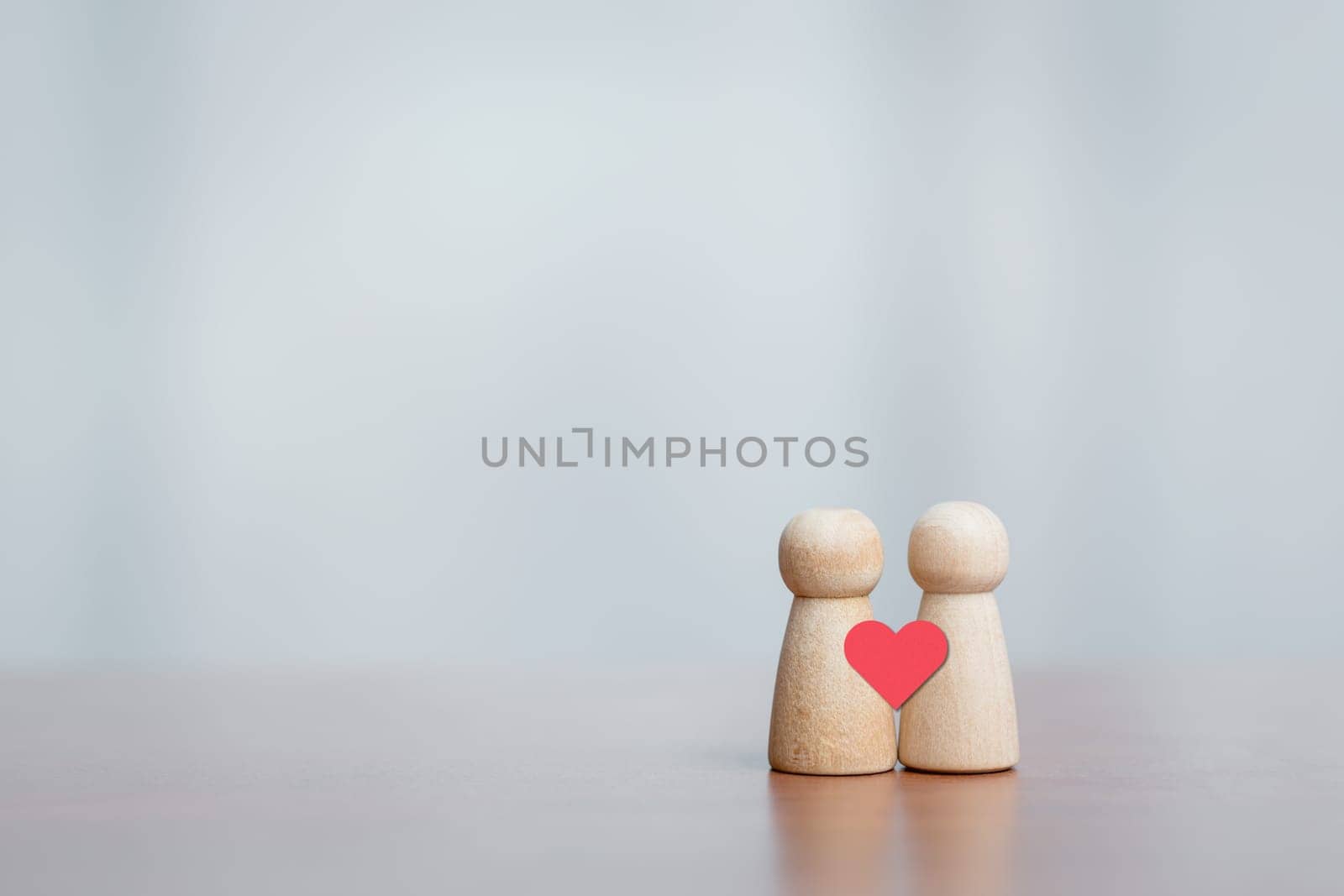 Two wooden figures with heart symbol. Concept of love, connection, relationship, empathy, care, and emotional bonding.