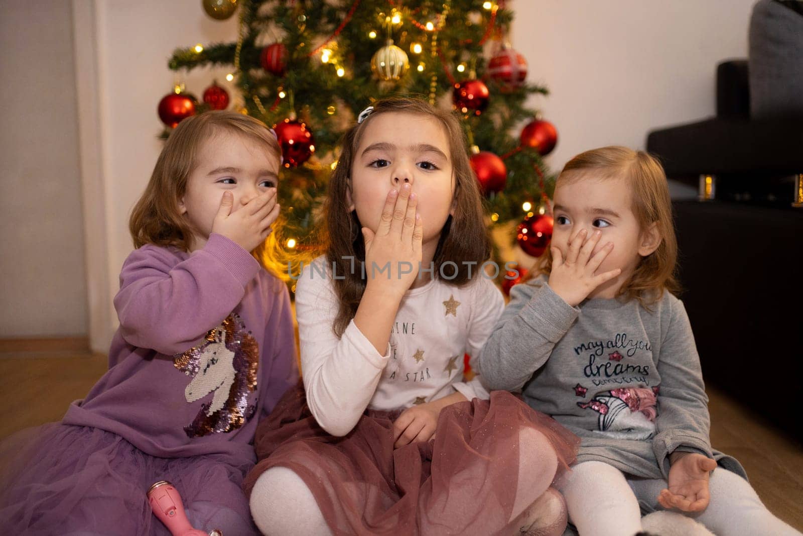 Three children are having fun together, making playful gestures.