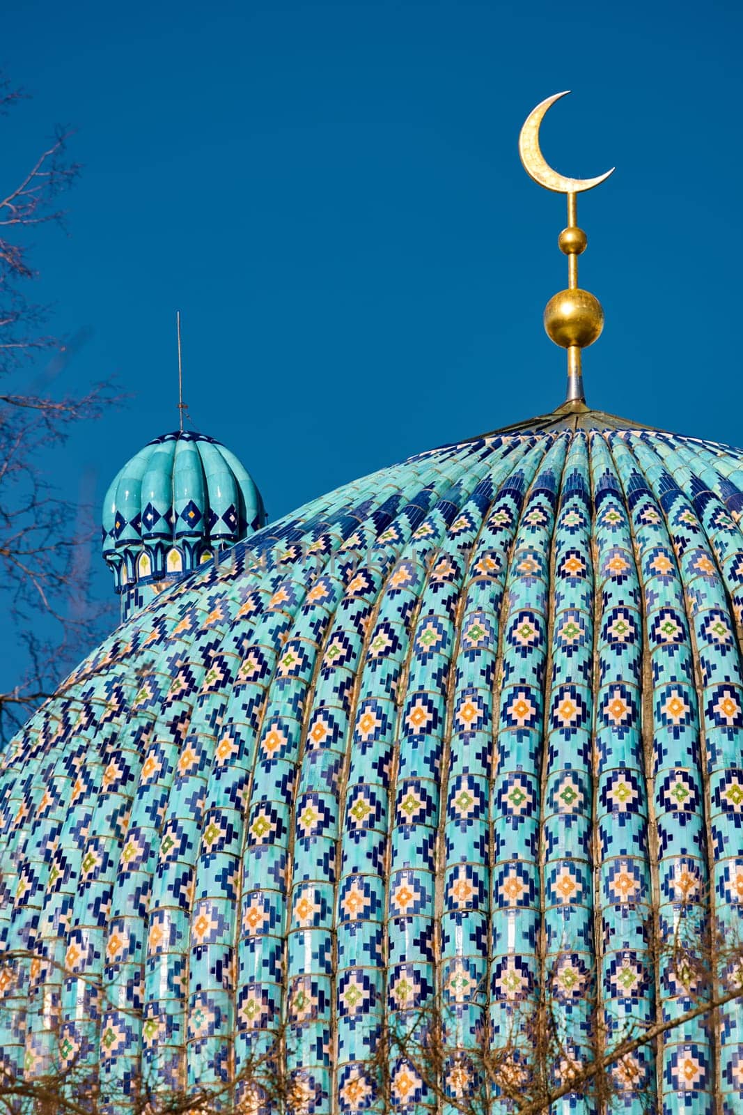 The blue dome with the golden crescent of the mosque in St.Petersburg - Russia through the branches of trees on a clear spring day. High quality photo