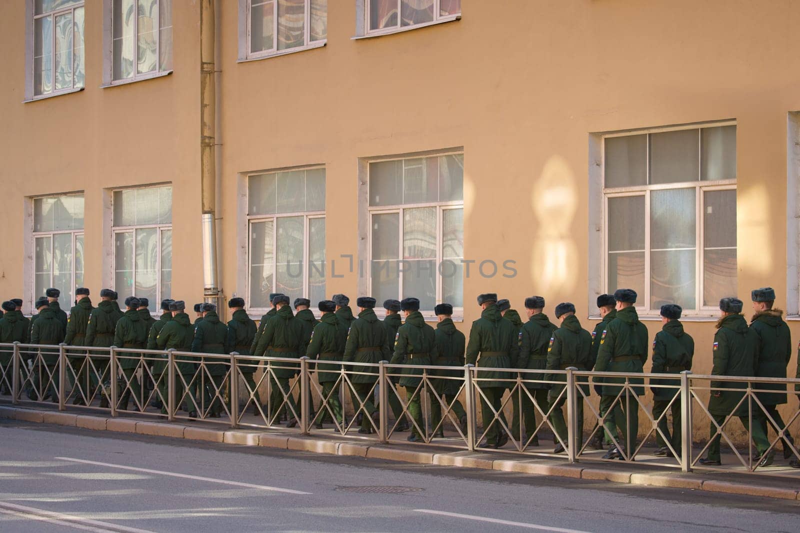 a column of cadets of military forces walk along the fence and gates with the symbols of the armed forces. High quality photo
