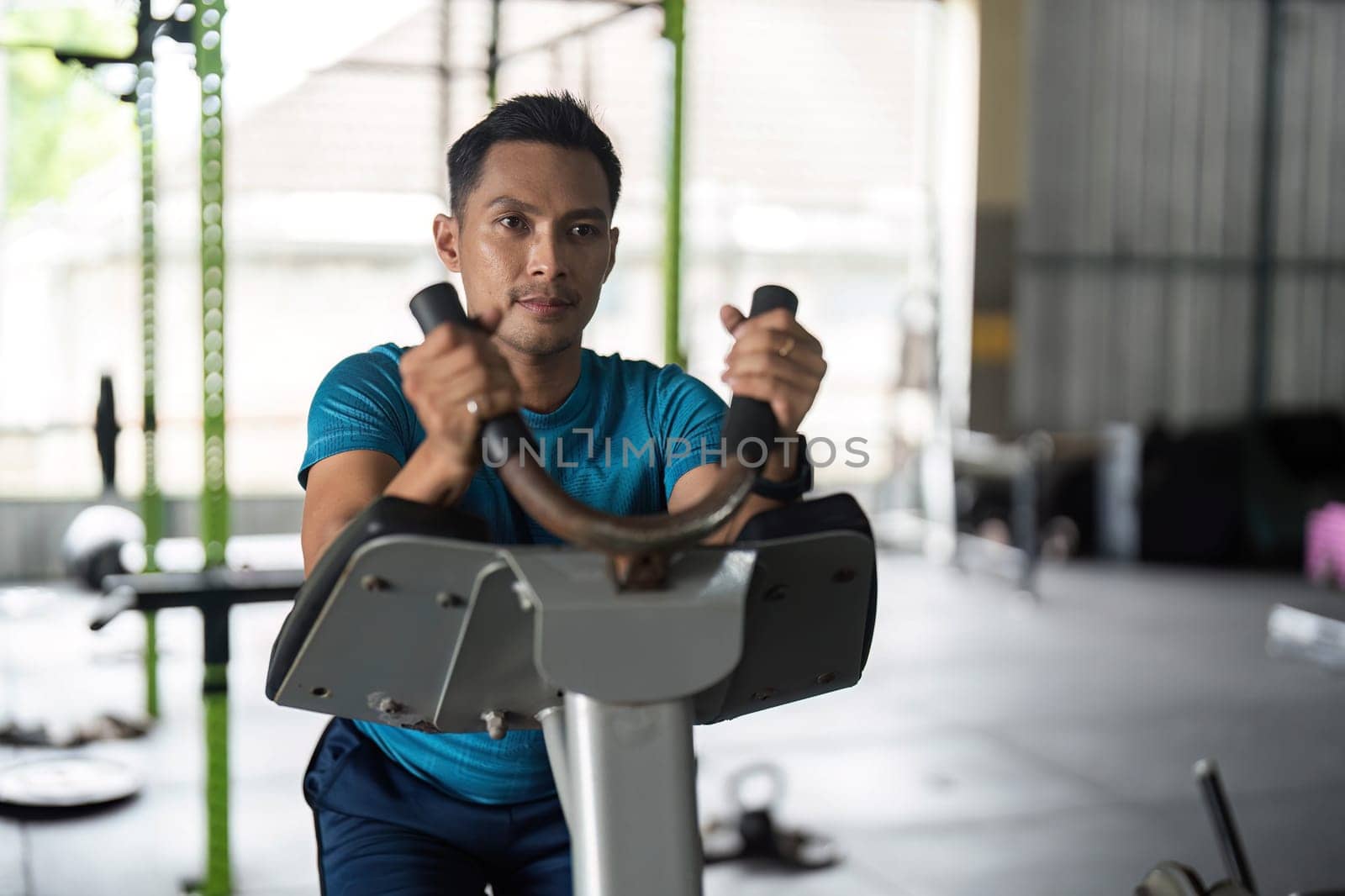 A man intensely focused on his workout while using an elliptical machine, representing dedication to fitness and healthy living.