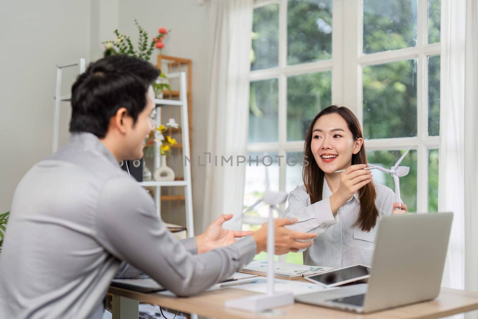 Two professionals engage in a consultation about renewable energy solutions, focusing on ESG strategies in a bright office setting.