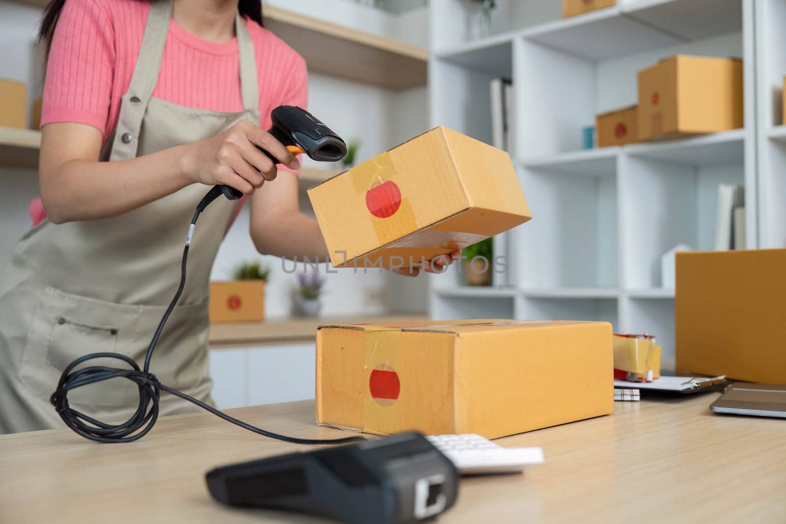 A young woman scans packages with a barcode reader, ensuring efficient inventory tracking in her retail workspace.