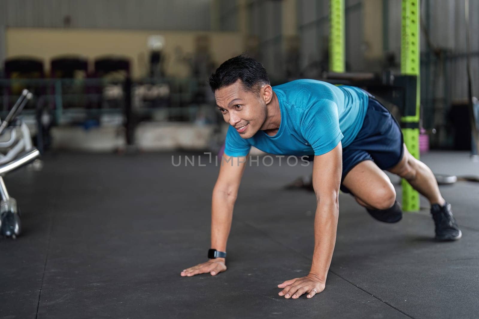 A man performs a push-up variation, demonstrating strength and commitment in a modern gym setting.