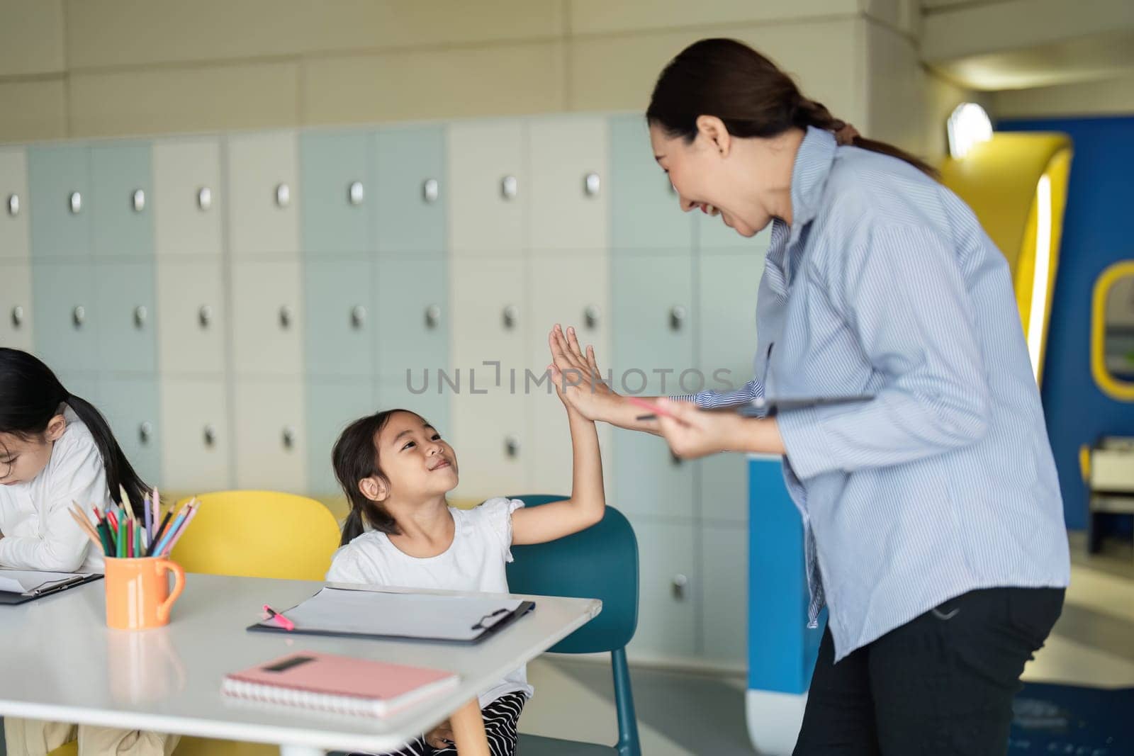 A teacher shares a joyful moment with a student, fostering a positive back-to-school atmosphere in the classroom.