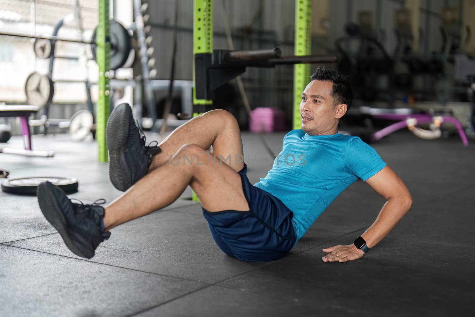 Athletic man executing bicycle crunches on gym floor, focusing on core strength and fitness routine.
