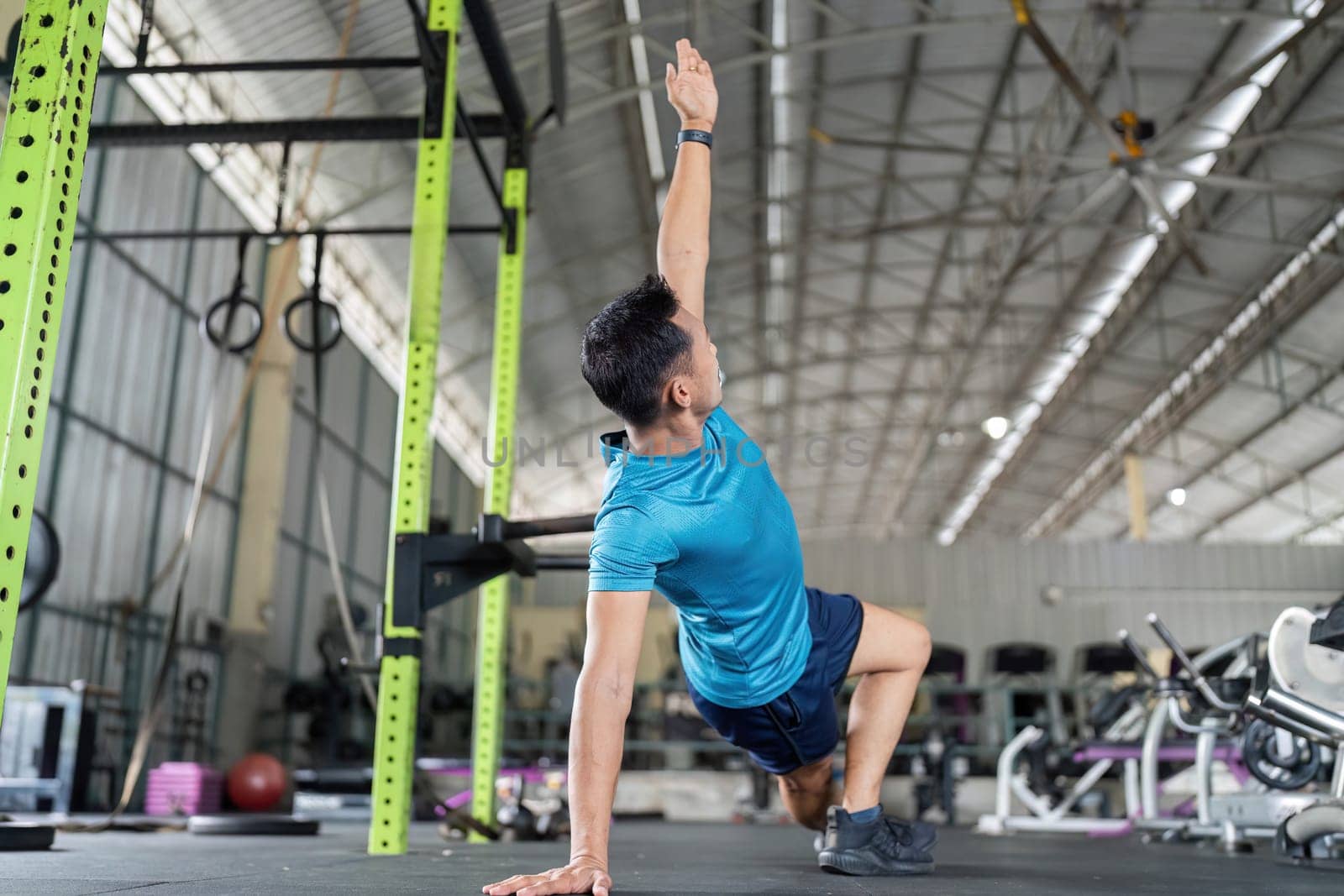 A male athlete performs a side plank reach, enhancing mobility and core strength in a fitness environment.