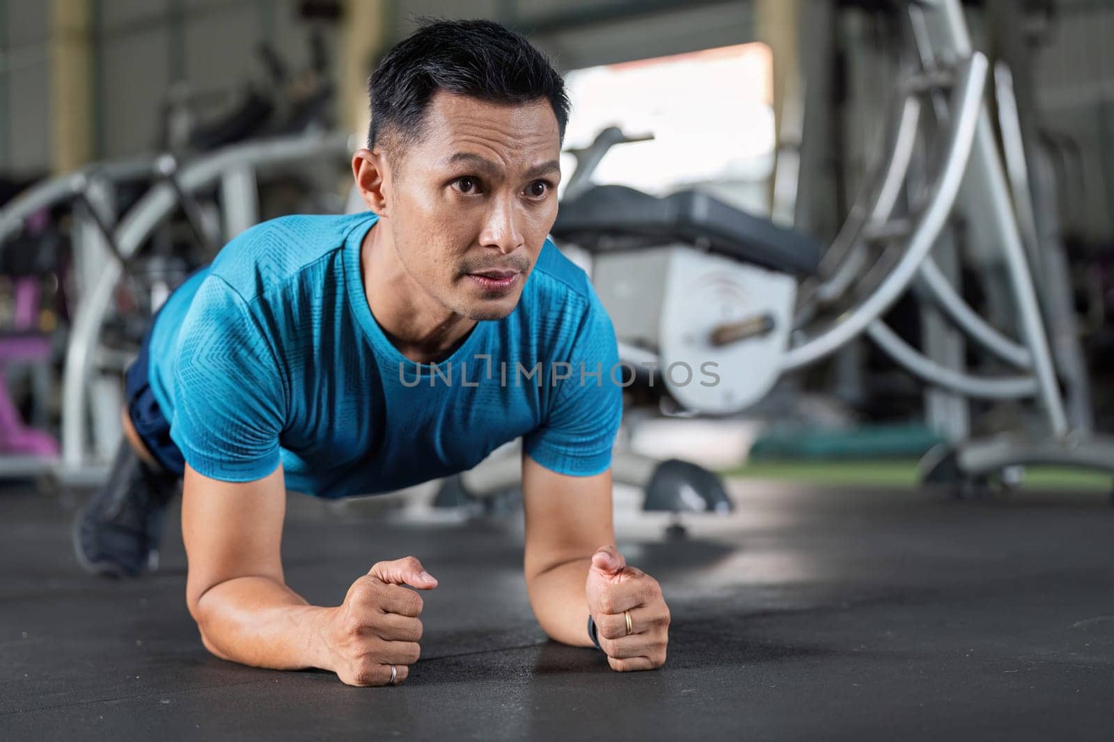 A man performs a plank exercise in a gym, focusing on core strength and stability as part of his fitness routine.