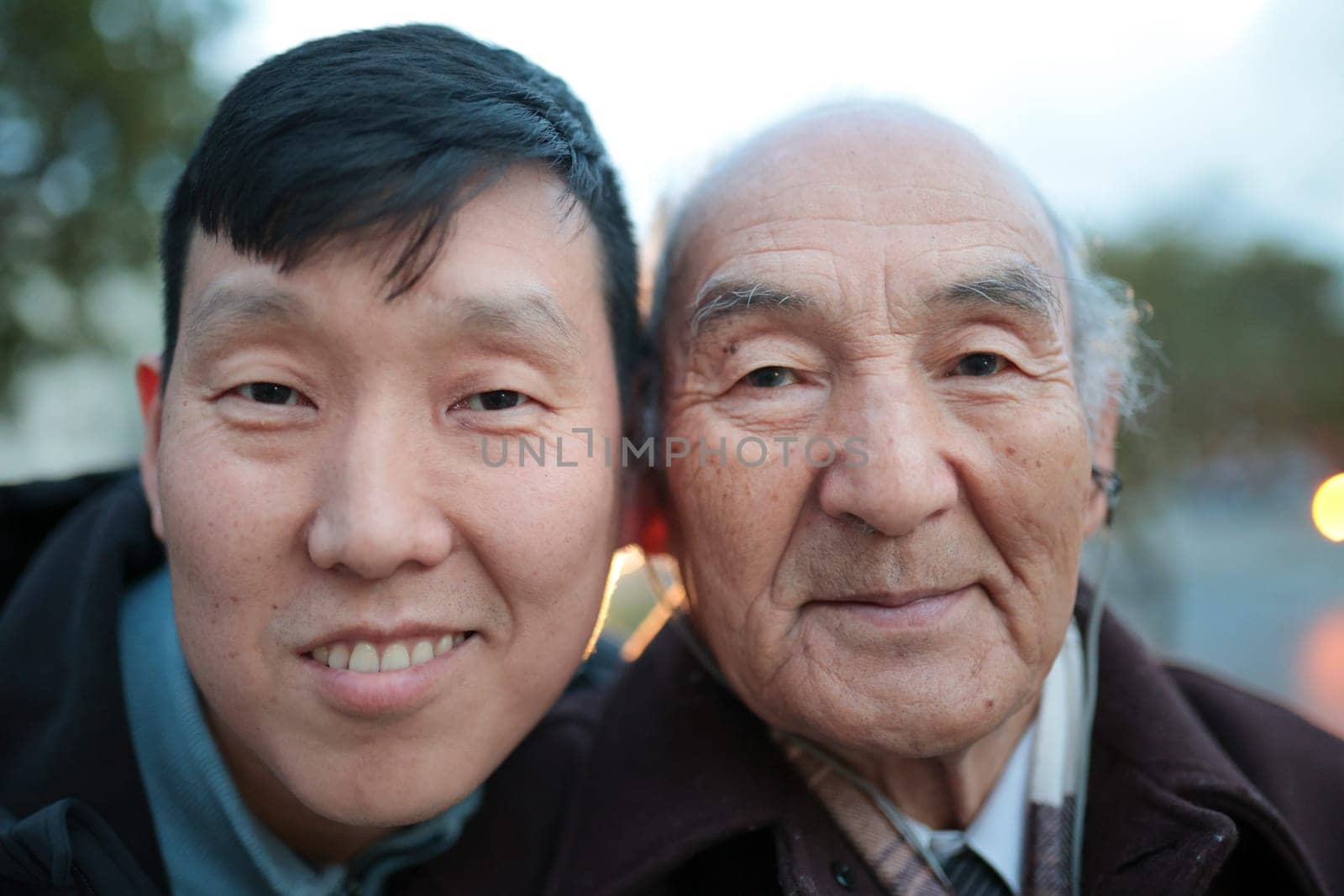 Happy father and son from asia posing together cheek to cheek outdoors