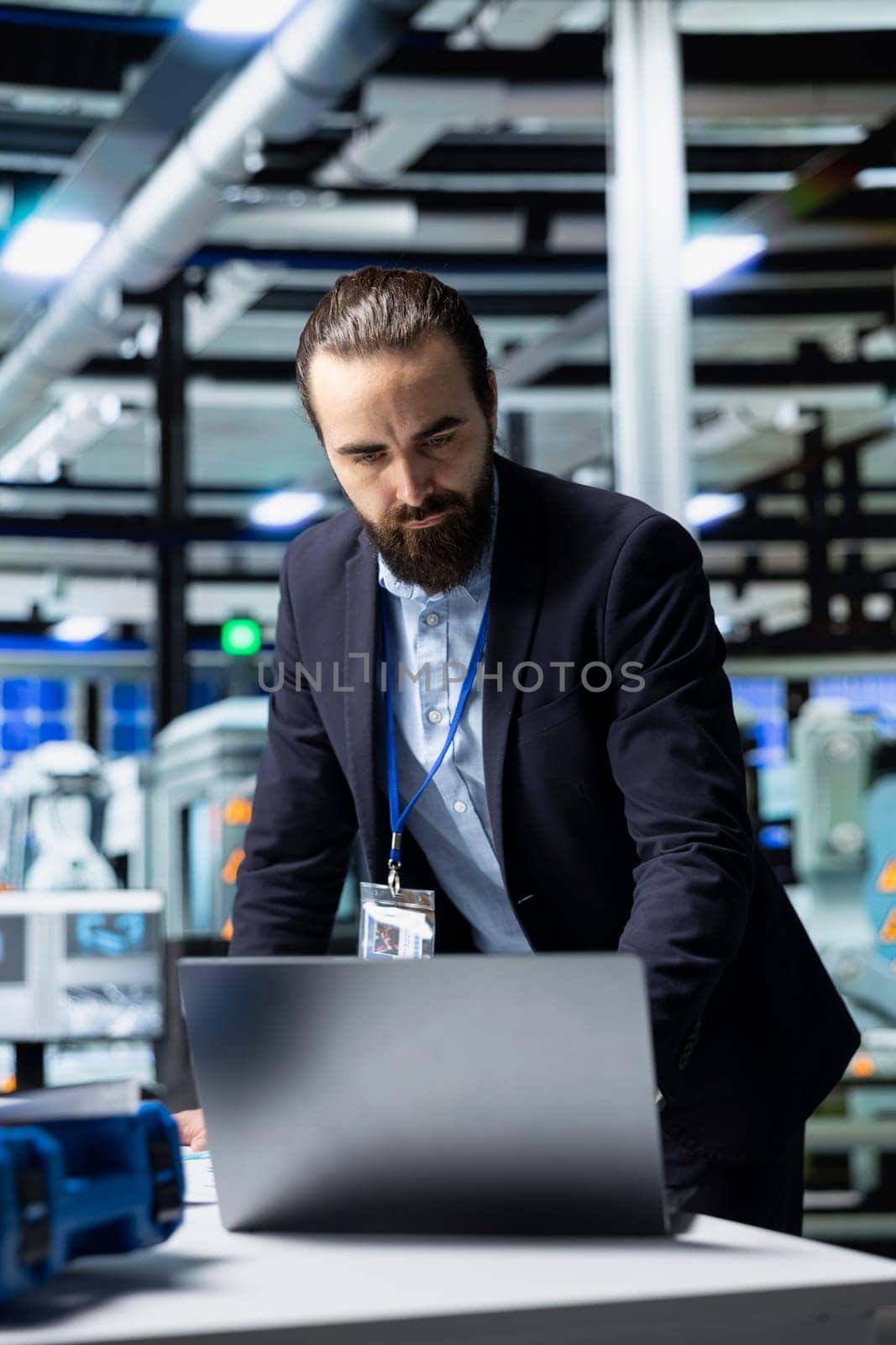 Facility supervisor in a suit monitoring solar panel production line, reflecting professional occupation and executive level involvement in renewable energy development. Solar power.