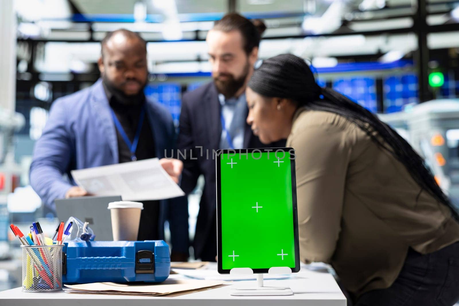 Team members in suits overseeing factory activity next to green screen, blending professionalism and technical expertise in the world of sustainable industrial energy. Cheaper power.